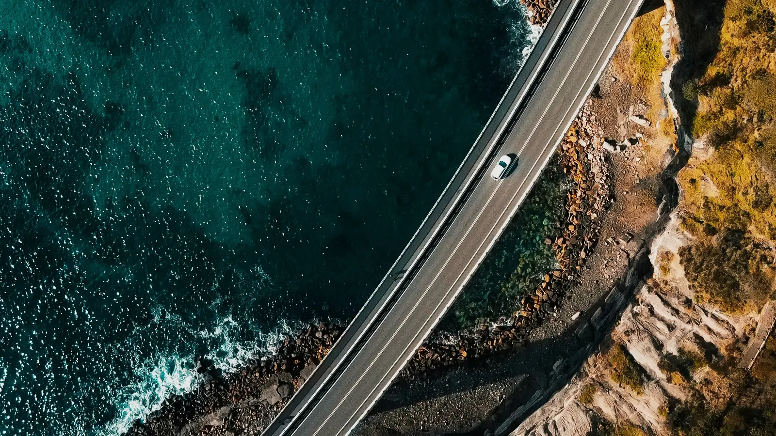 A coast road running along the cliffs above the sea, seen from above.