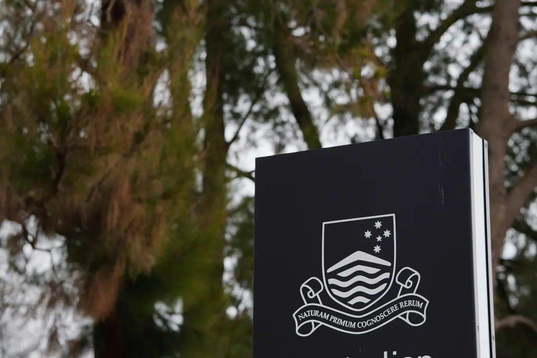 The Australian National University sign among gum trees in Canberra.