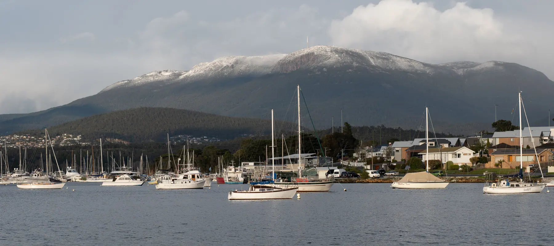 Yachts moored in Hobart below kunanyi / Mount Wellington, dusted with snow.