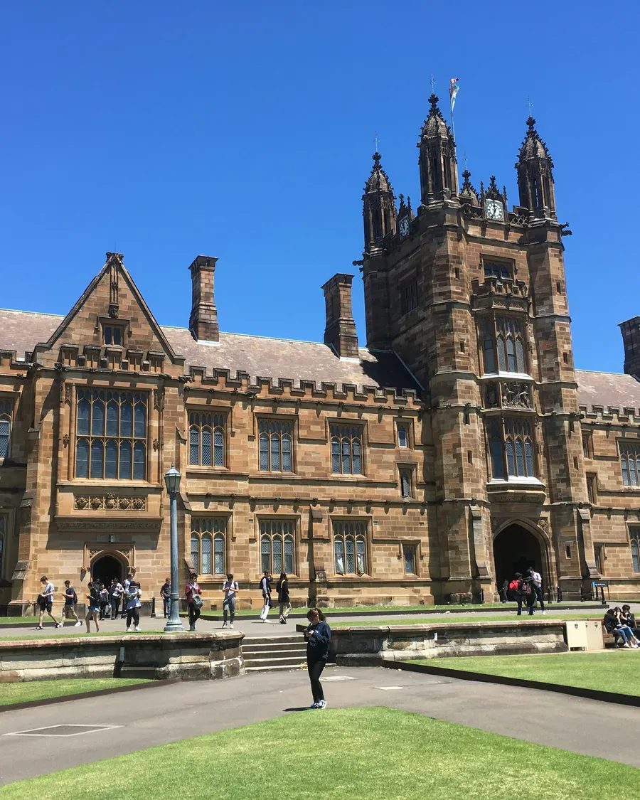 The Quadrangle at the University of Sydney, with students walking across the lawn.