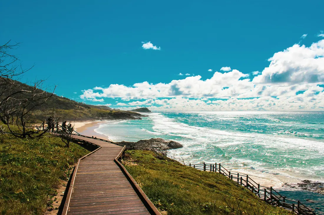 A boardwalk running above a wide surf beach.